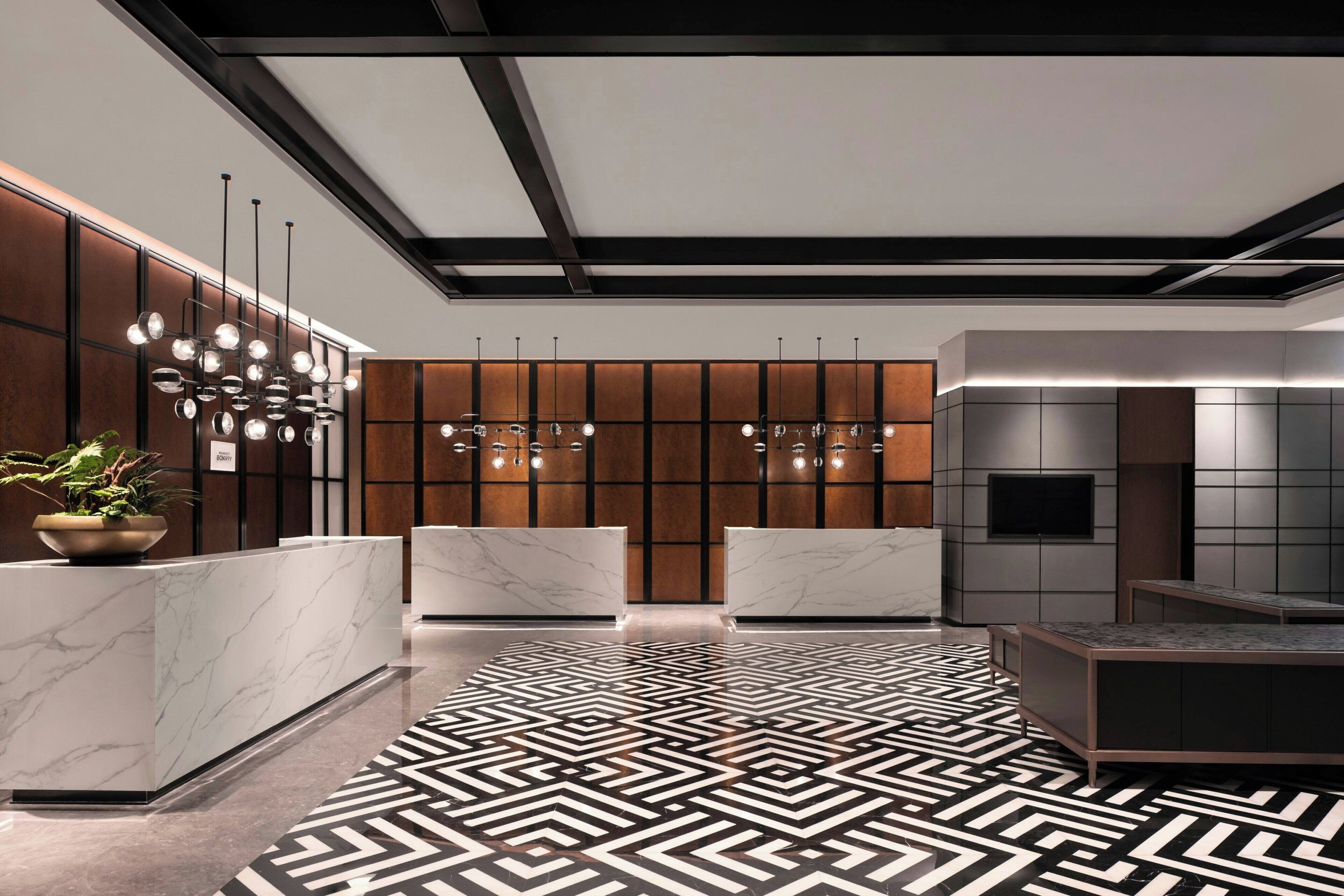 A modern reception area with marble counters, a geometric patterned floor, and pendant lighting.