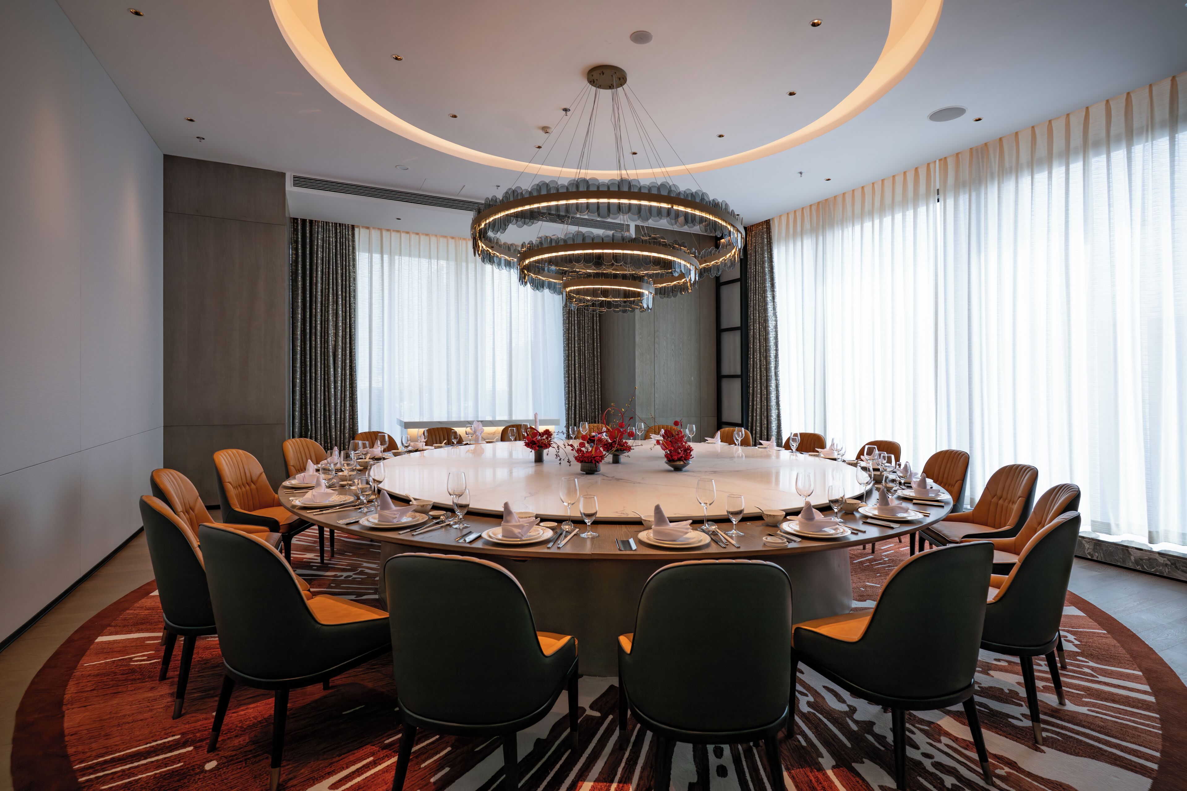 A conference room with a round table, chairs, and a chandelier.