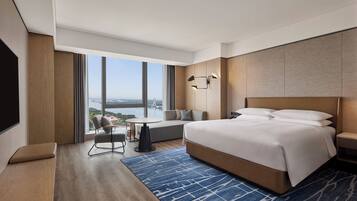 Ein modernes Hotelzimmer mit einem großen Bett, einer Sitzecke mit Blick und einem Flachbildfernseher.