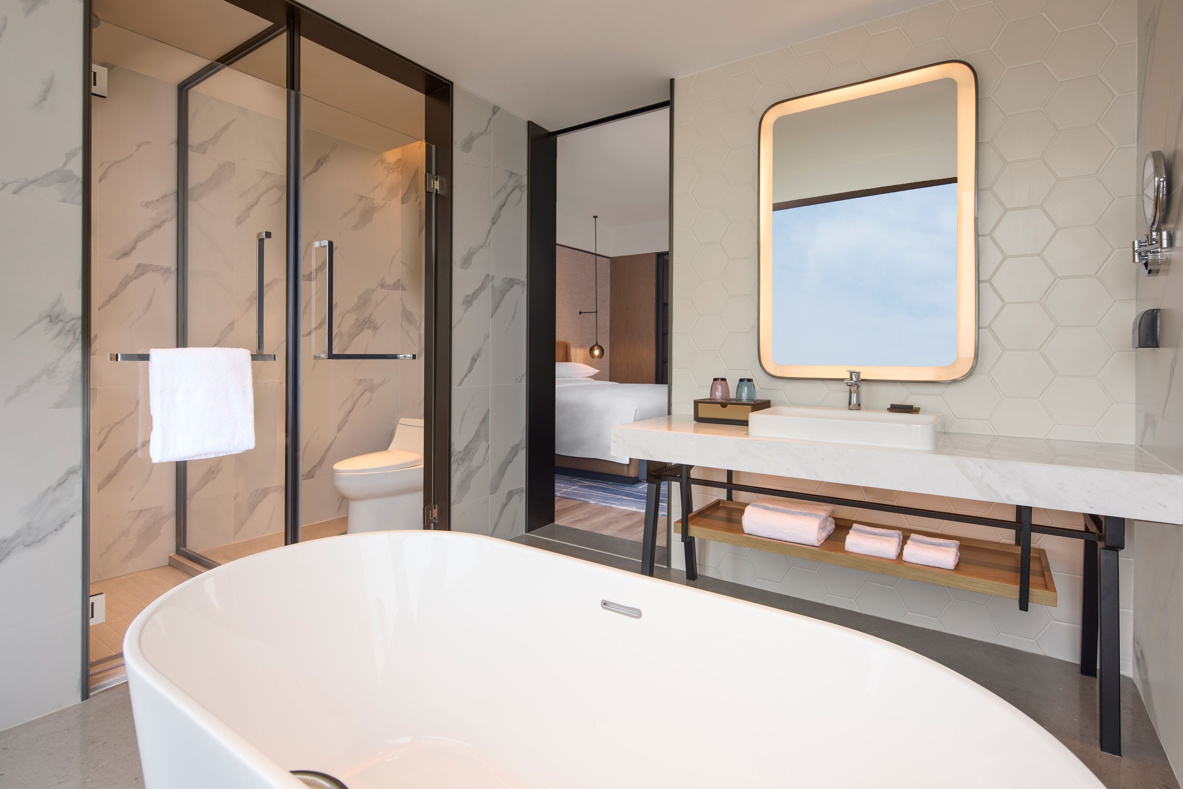 A modern bathroom with a freestanding bathtub, a glass shower enclosure, and a vanity with a large mirror.