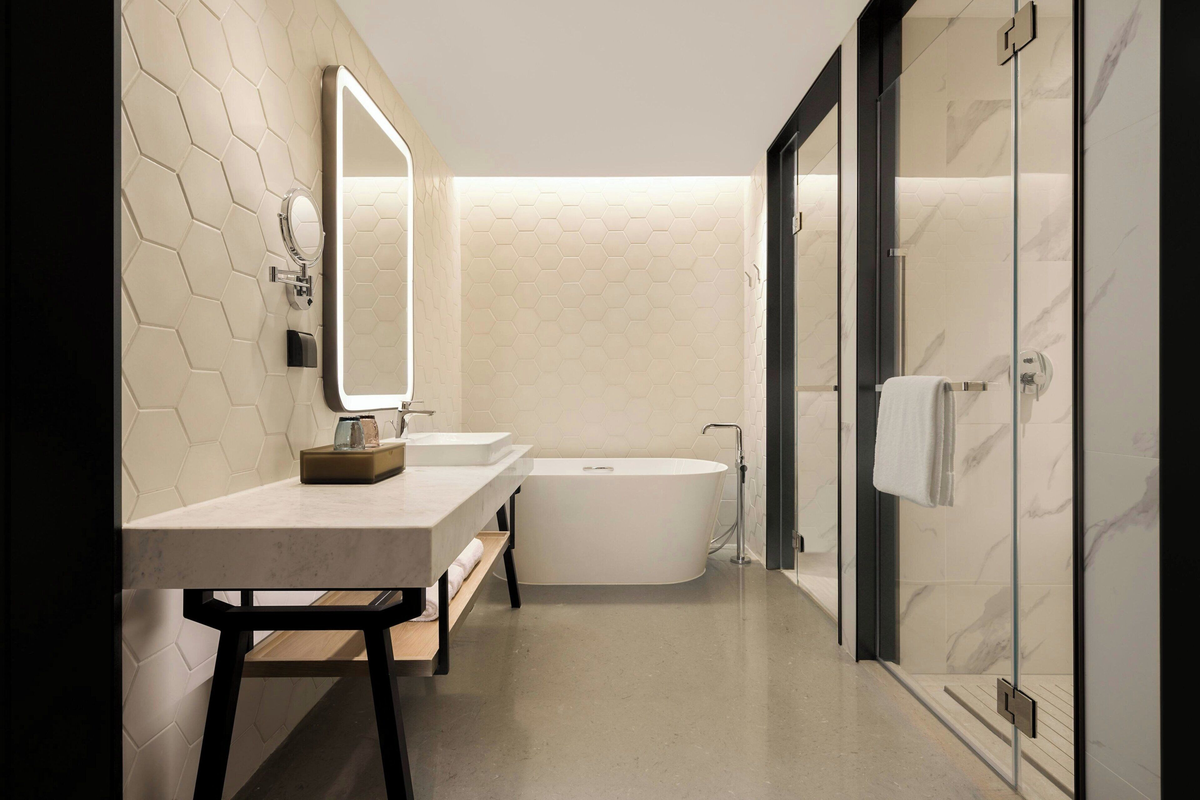 A modern bathroom with a freestanding bathtub, a vanity with a mirror, and a towel rack.