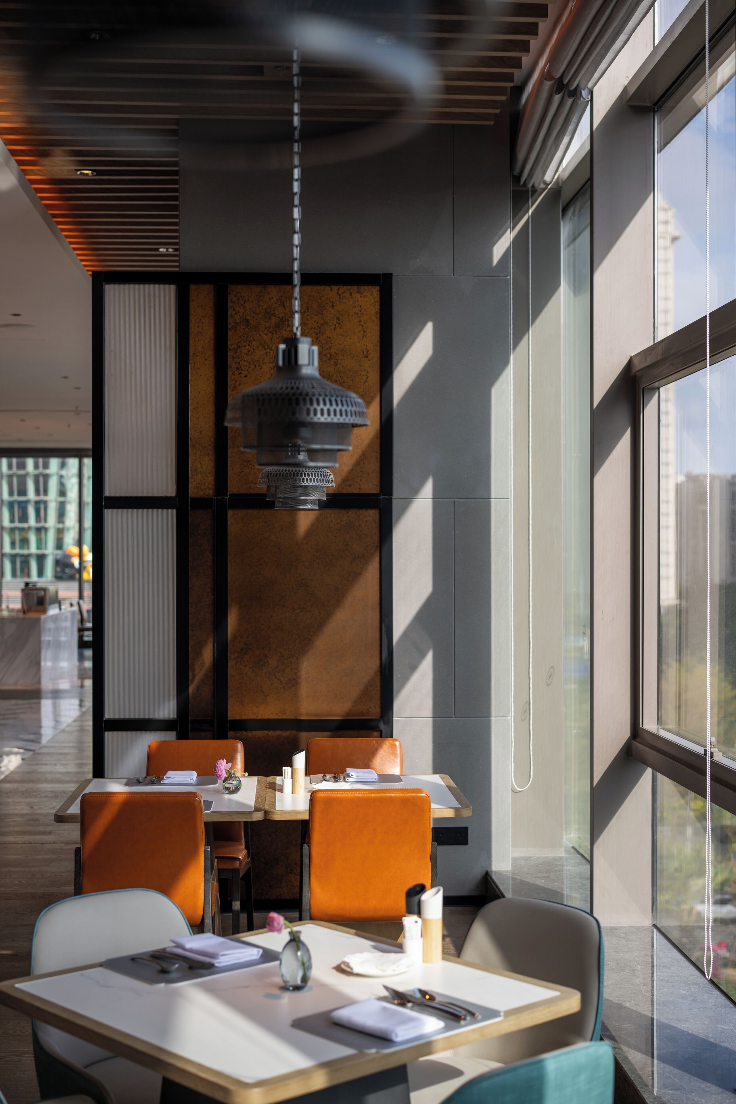Un área de comedor moderna con una mesa grande, sillas naranjas y una lámpara colgante.
