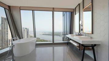 Un baño moderno con una bañera grande, dos lavamanos y un amplio ventanal con vistas a la ciudad.