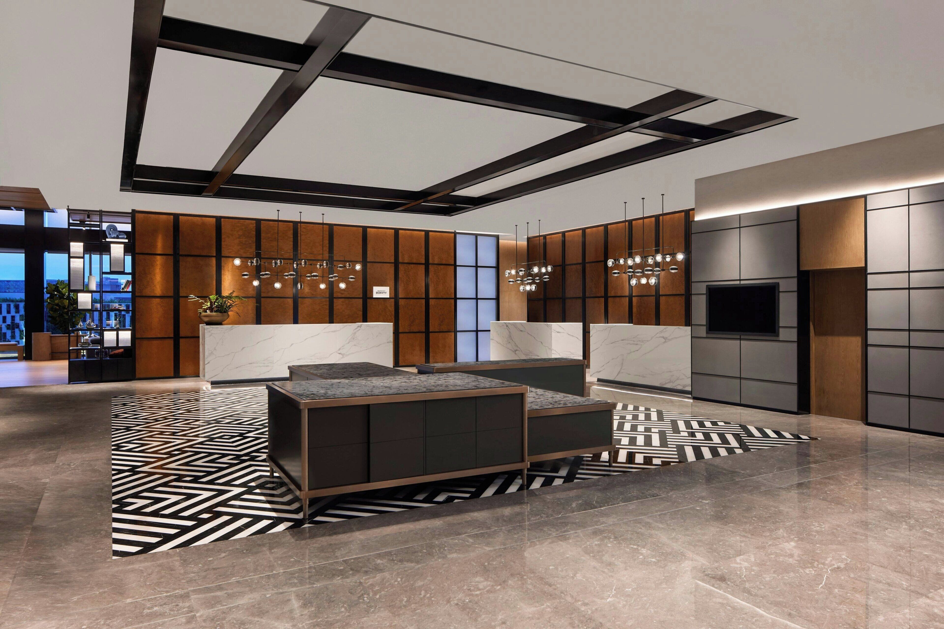 A modern lobby with a reception desk, seating area, and a large TV screen.