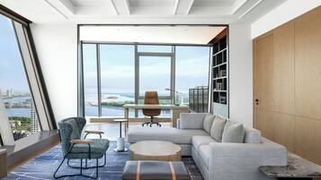 A modern living room with a large window, a sofa, a chair, a coffee table, and a wooden cabinet.