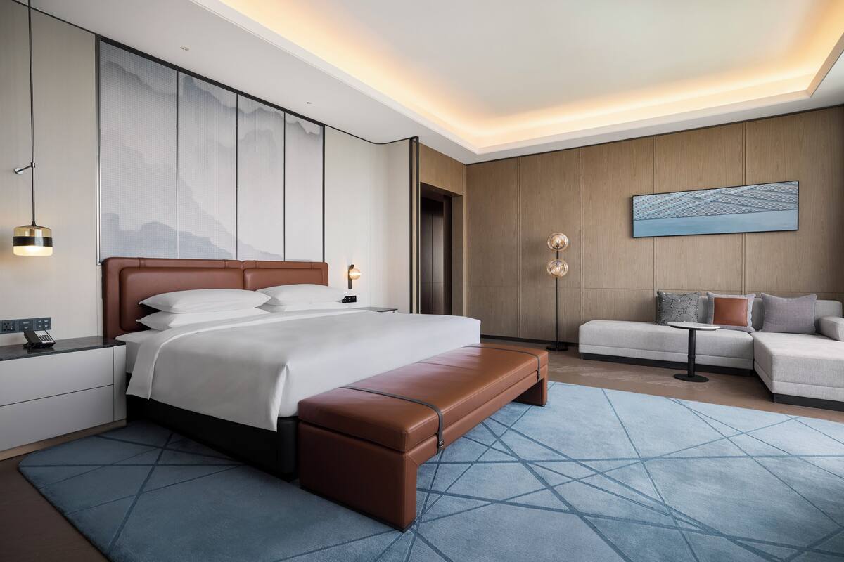 Ein modernes Hotelzimmer mit einem großen Bett, einer Bank, einem Sofa und einem kleinen Tisch.