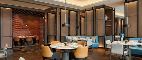 A modern restaurant with round tables, cushioned seating, and pendant lighting.