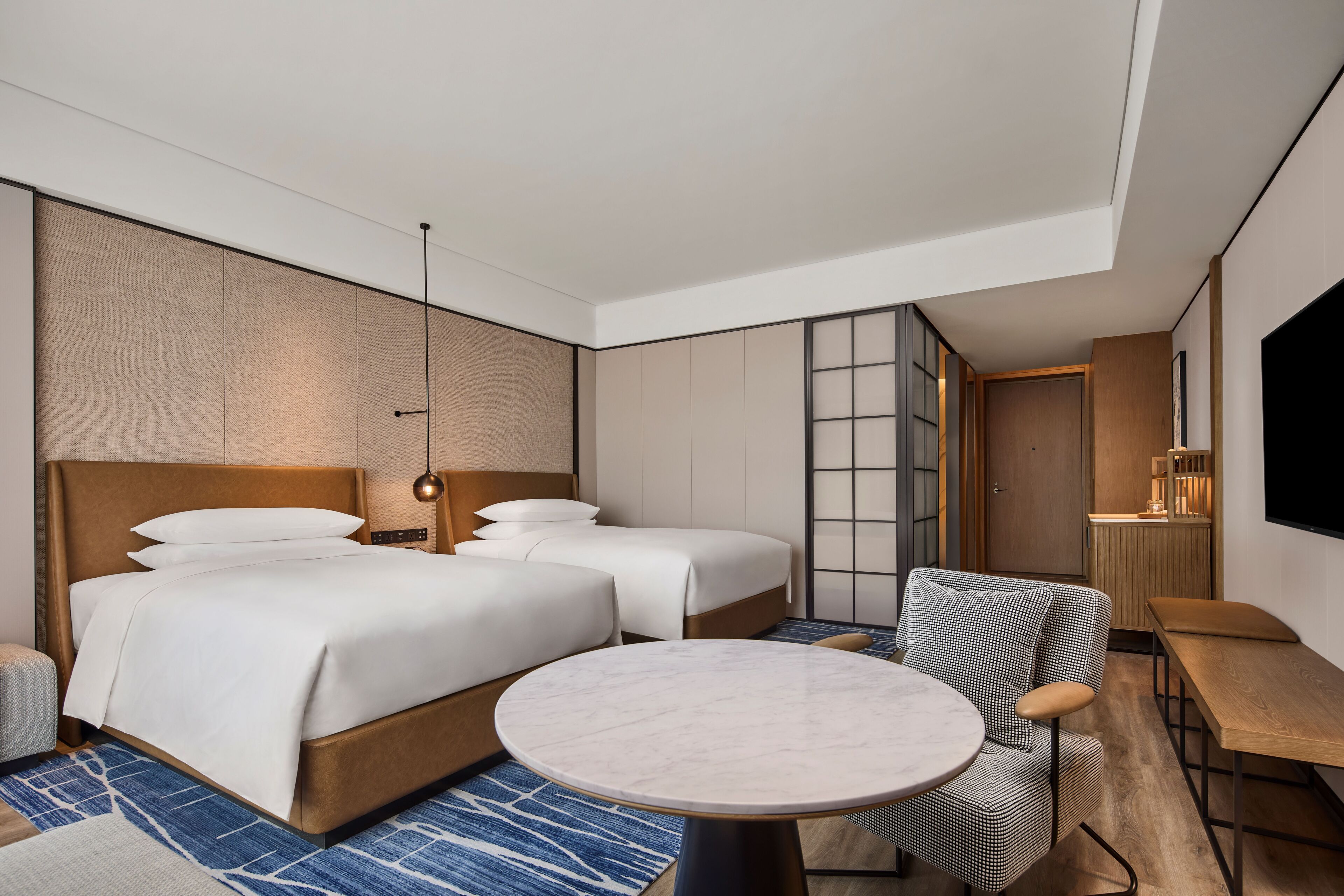 Una habitación de hotel moderna con una cama grande, una mesa redonda y una zona de estar.