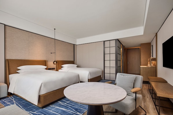 Una habitación de hotel moderna con una cama grande, una mesa redonda y una zona de estar.