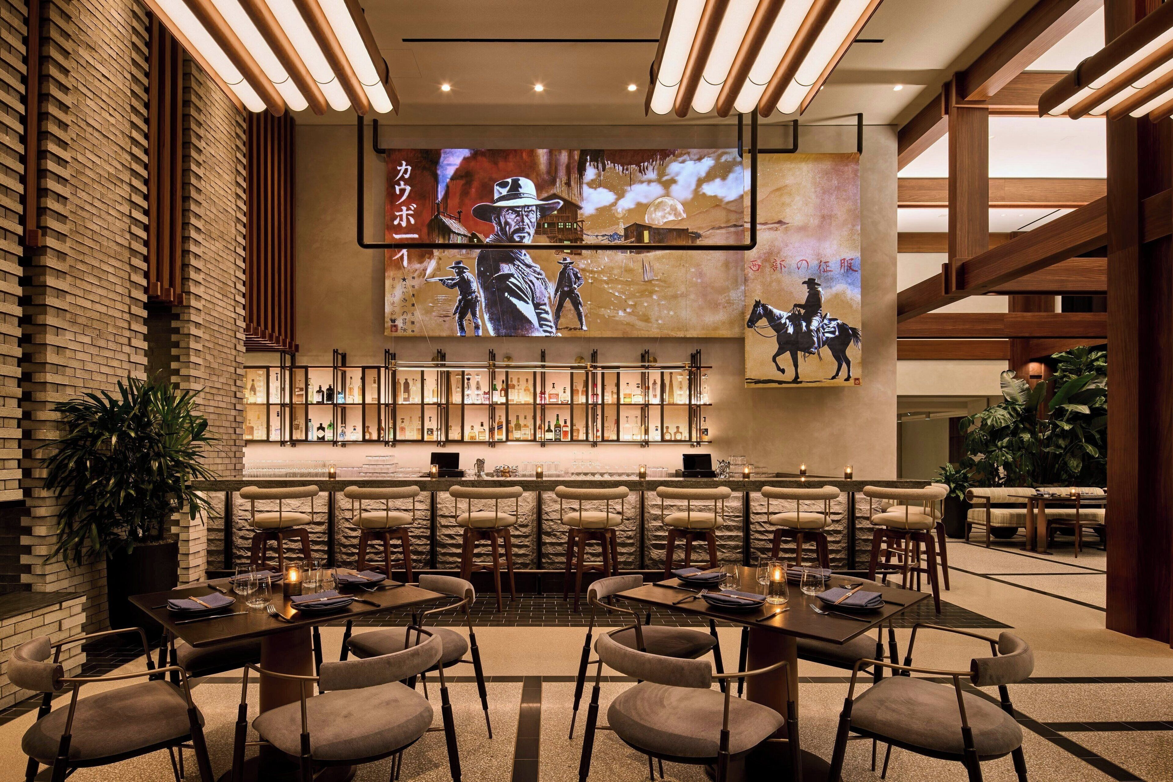 A modern bar area with multiple seating options, a large screen displaying a movie scene, and a well-lit interior.