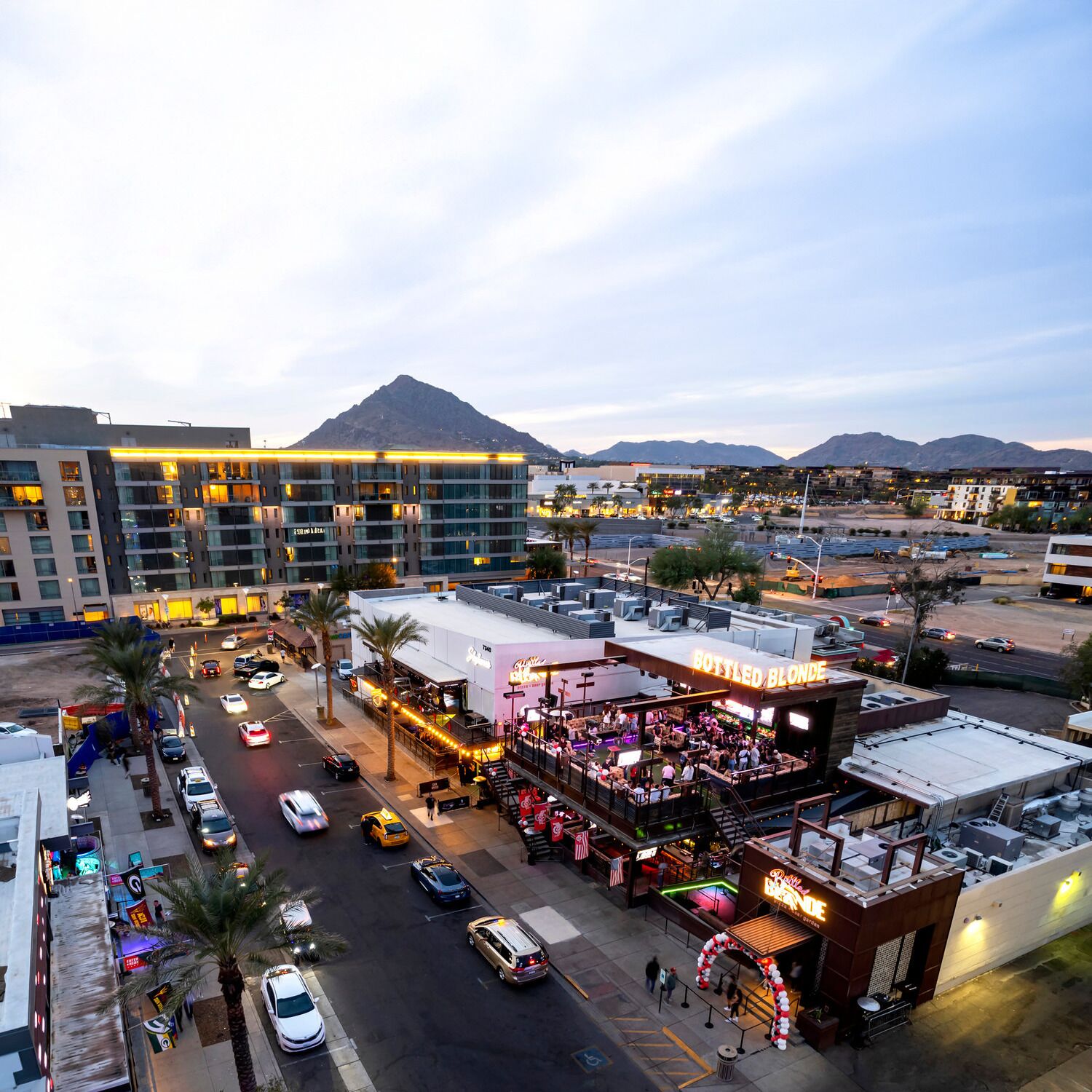 A hotel with multiple floors, a rooftop bar, and a view of mountains in the background.