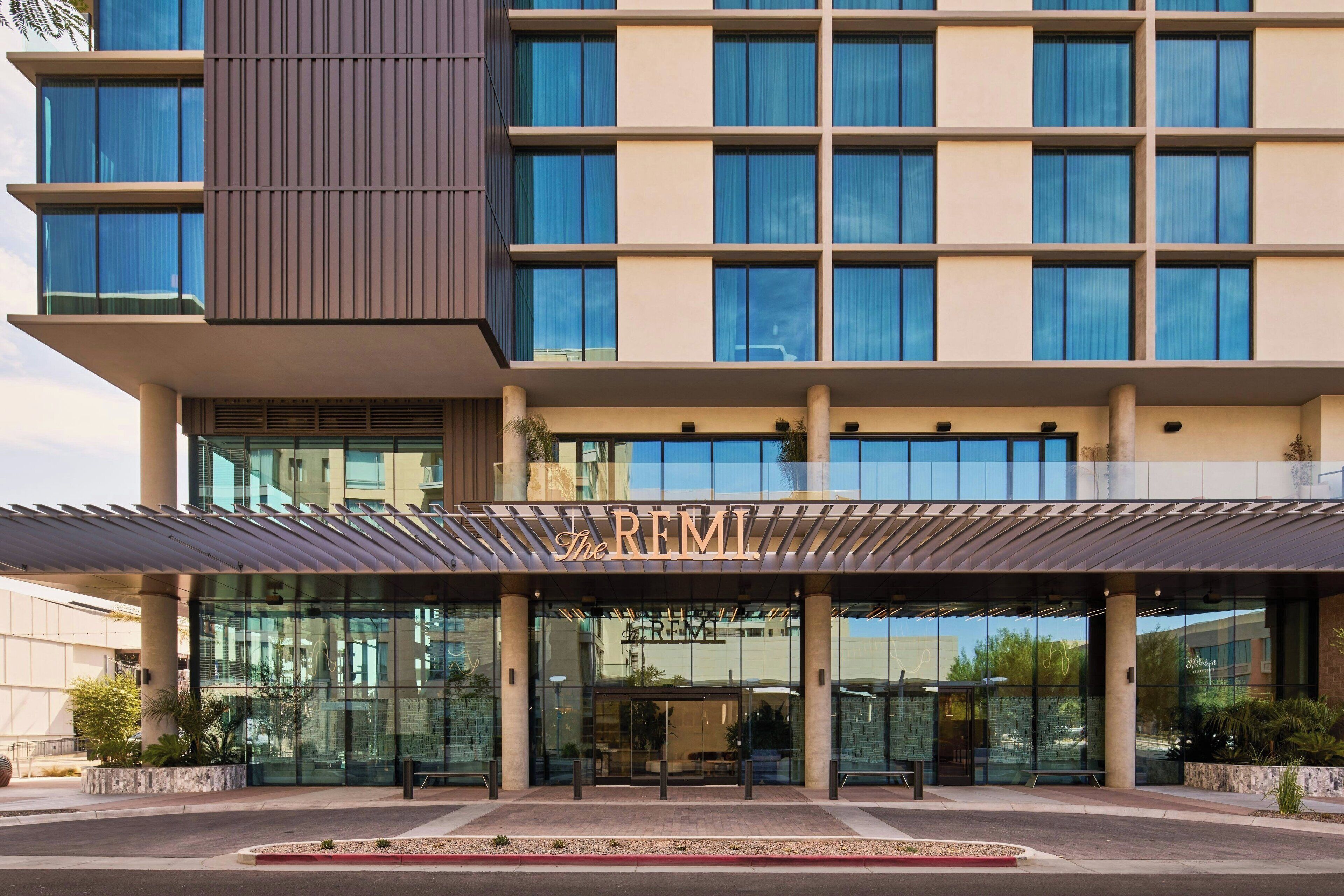 A modern hotel with a prominent entrance, large windows, and a covered walkway.