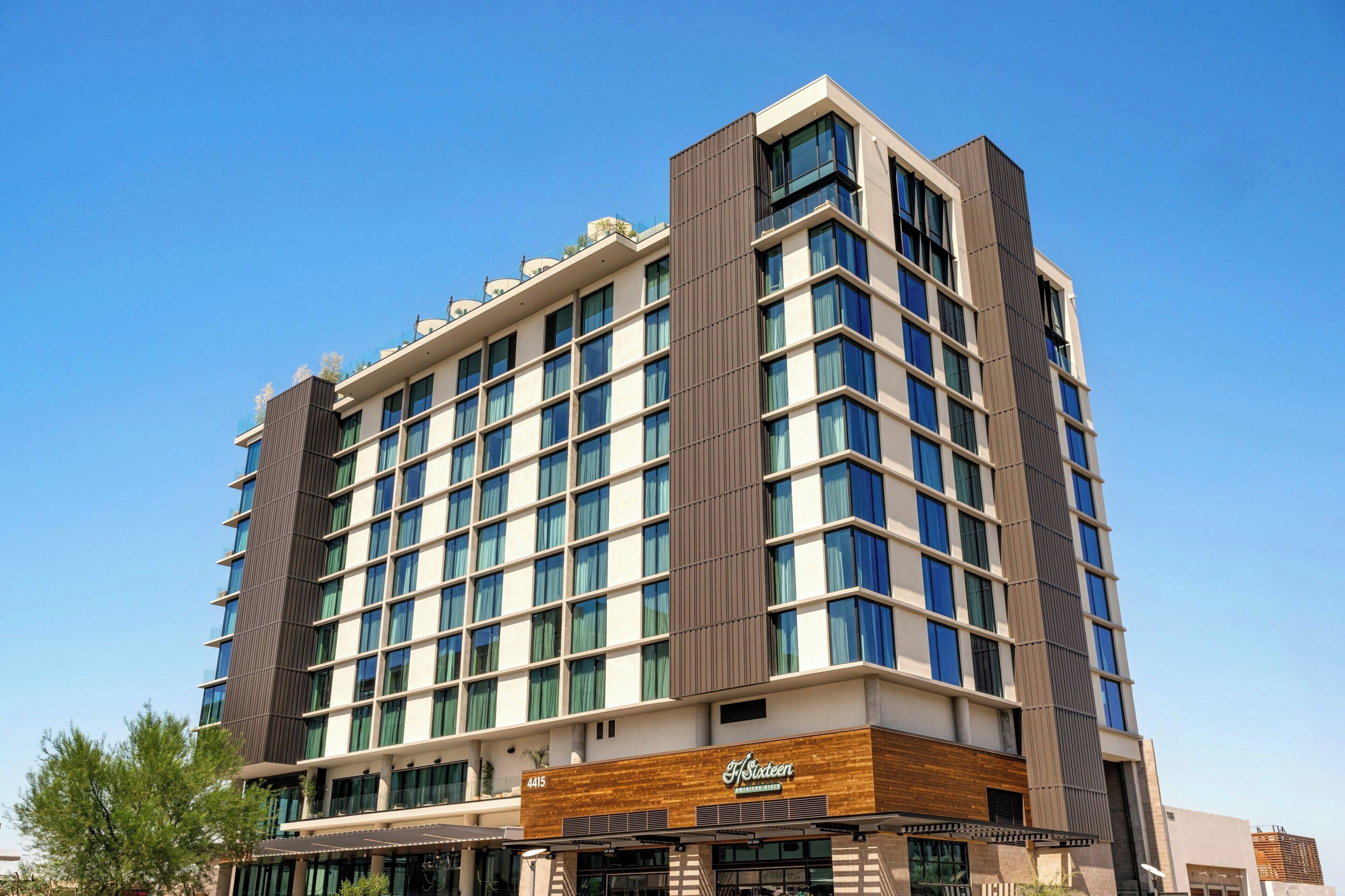 A multi-story hotel with a modern design, featuring a prominent vertical wooden panel on the facade, large windows, and a sign indicating it is a Marriott hotel.