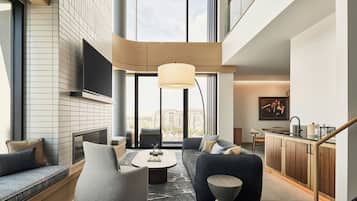 Un salon moderne comprenant un canapé, un fauteuil, une table basse et un téléviseur fixé au mur.