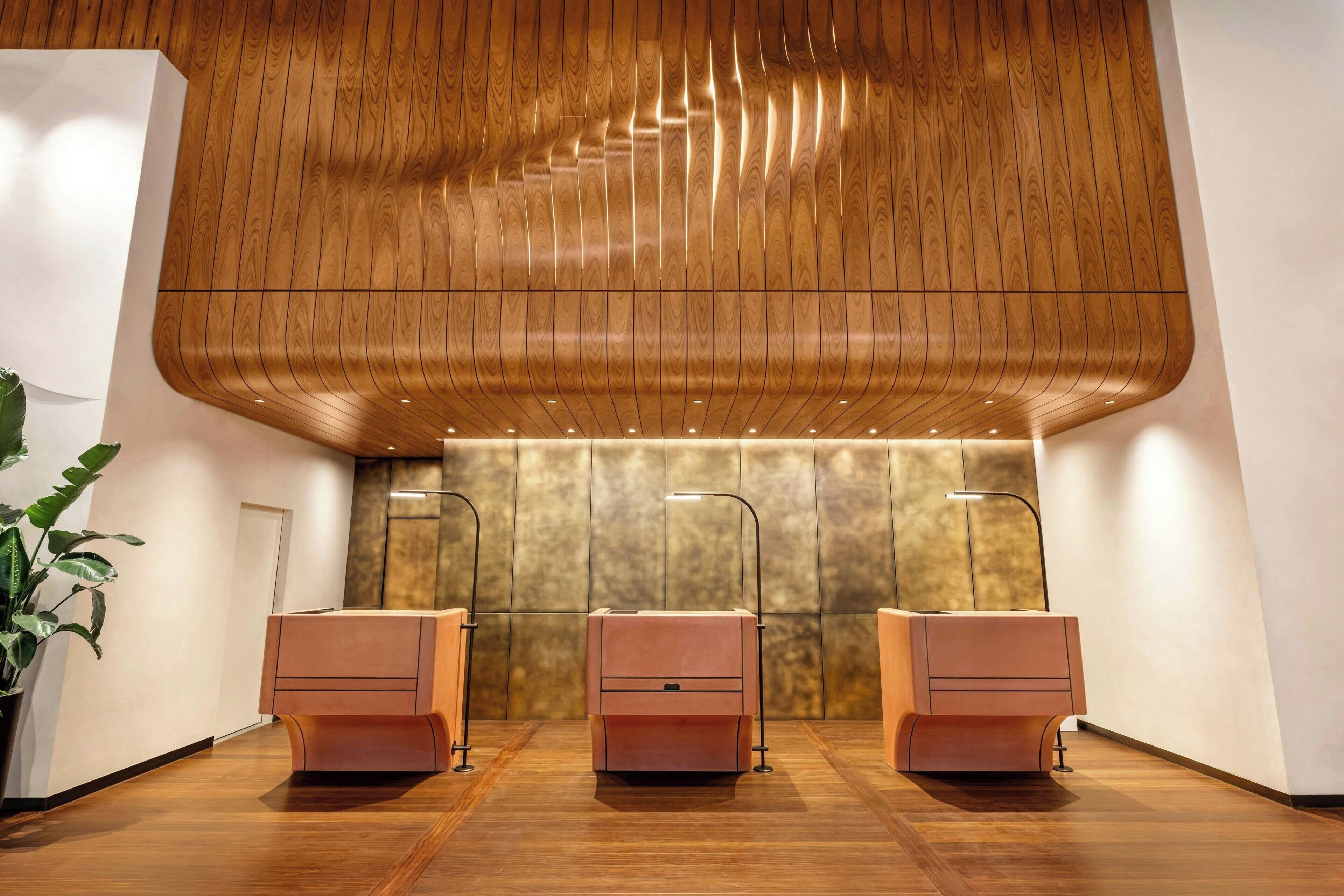 A modern bathroom with wooden ceiling panels, three sinks, and a large mirror.