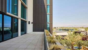 Un edificio moderno con ventanas amplias, una terraza con baldosas y vistas del entorno.
