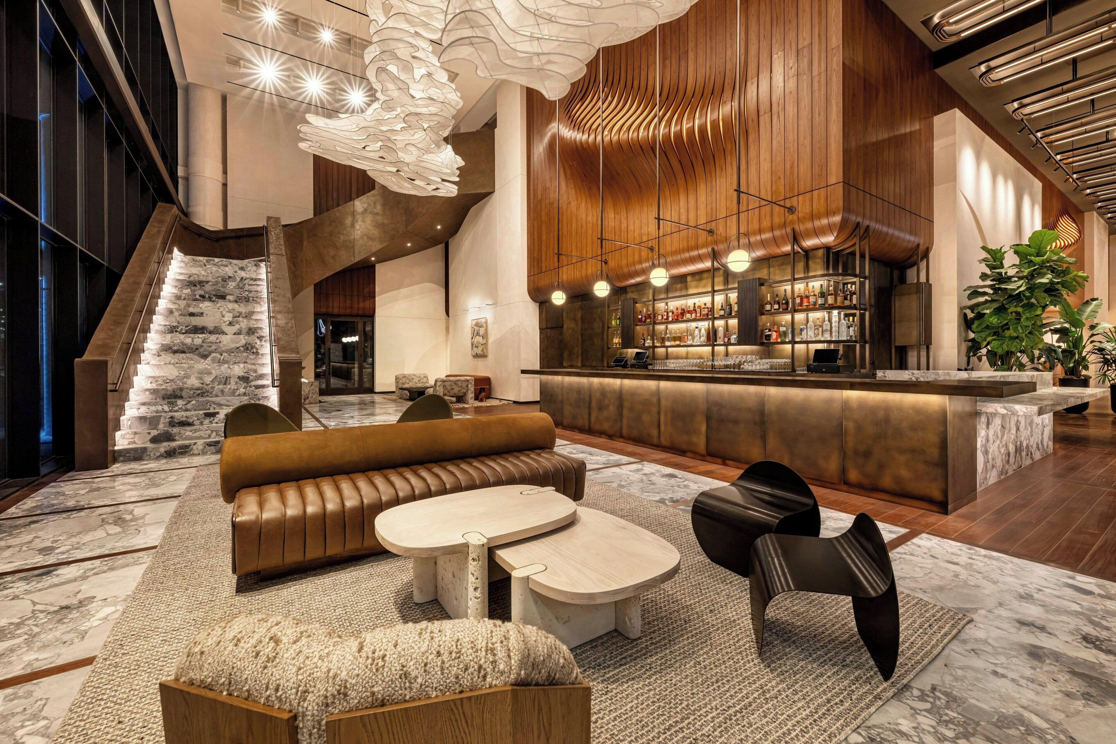 A modern lobby with a bar area, seating, and a staircase.