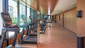 A fitness center with treadmills and exercise equipment, large windows, and a wooden floor. - Bloomfields Modern 1Br Bingahtti Onyx (Dubai)