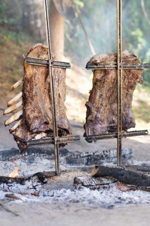 Two racks of meat being grilled over an open fire.