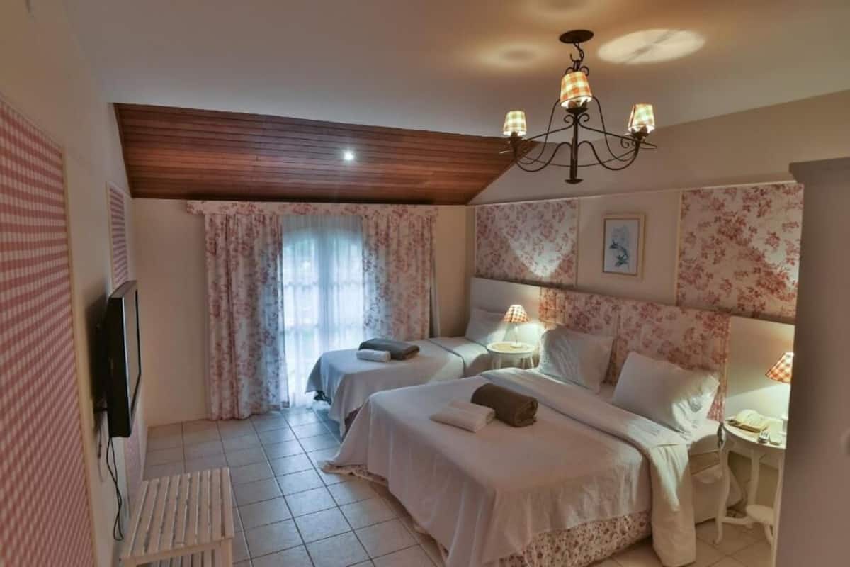 Ett hotellrum med två sängar, en TV, ett skrivbord med en lampa och en kristallkrona.