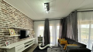 Una sala de estar moderna con pared de ladrillo, televisor de pantalla plana, sofá y mesa de centro.