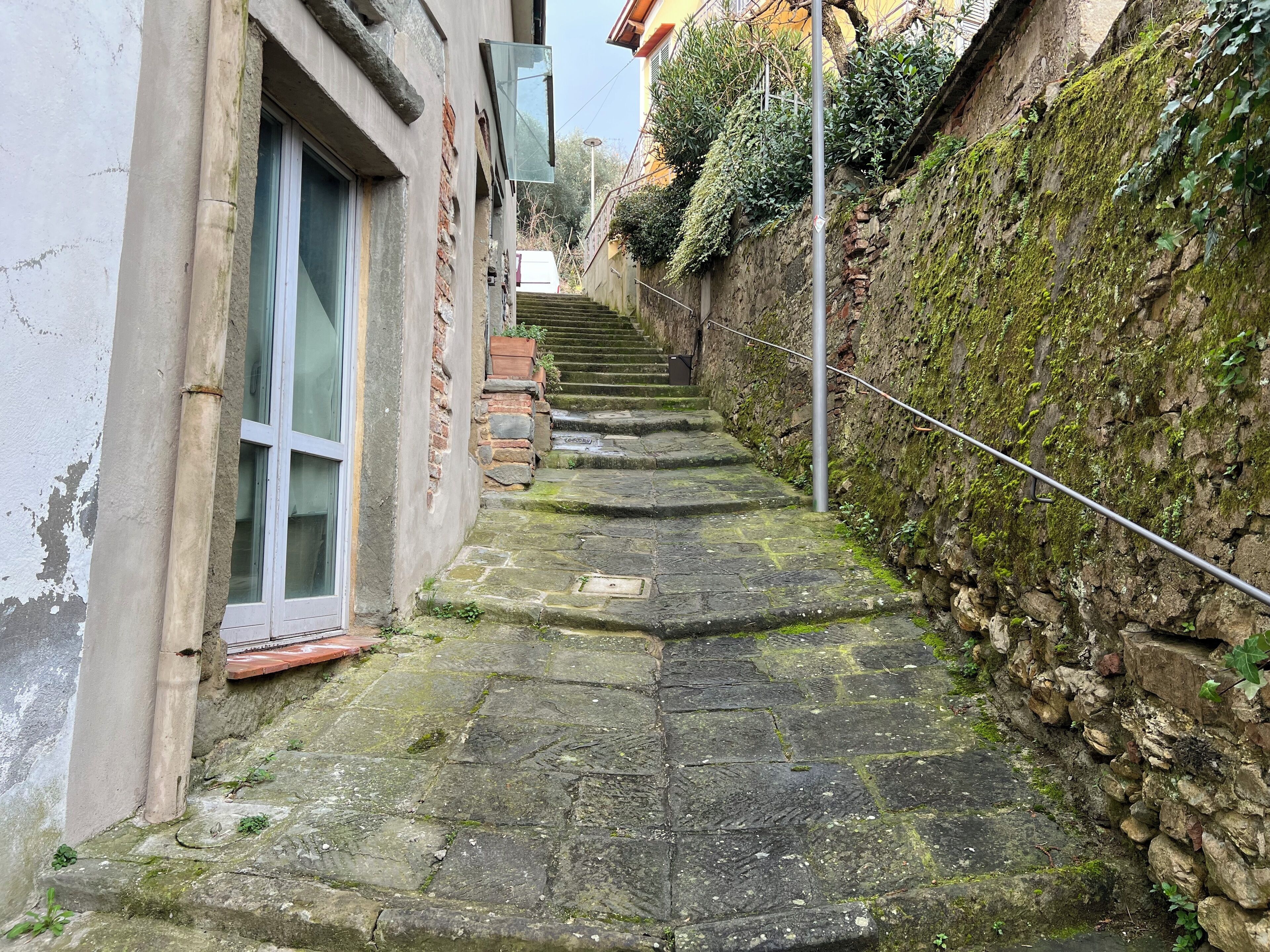 Un escalier étroit en pierre mène à un bâtiment doté d’une fenêtre et d’une porte.