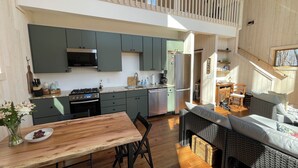 Een ruime keuken met moderne apparatuur en een eethoek met een houten tafel en rieten meubilair.