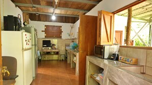 A compact kitchen with basic appliances, a tiled floor, and wooden cabinets. - 4-bedroom house in fabulous Isla de Ometepe with AC, WiFi (Isla de Ometepe)