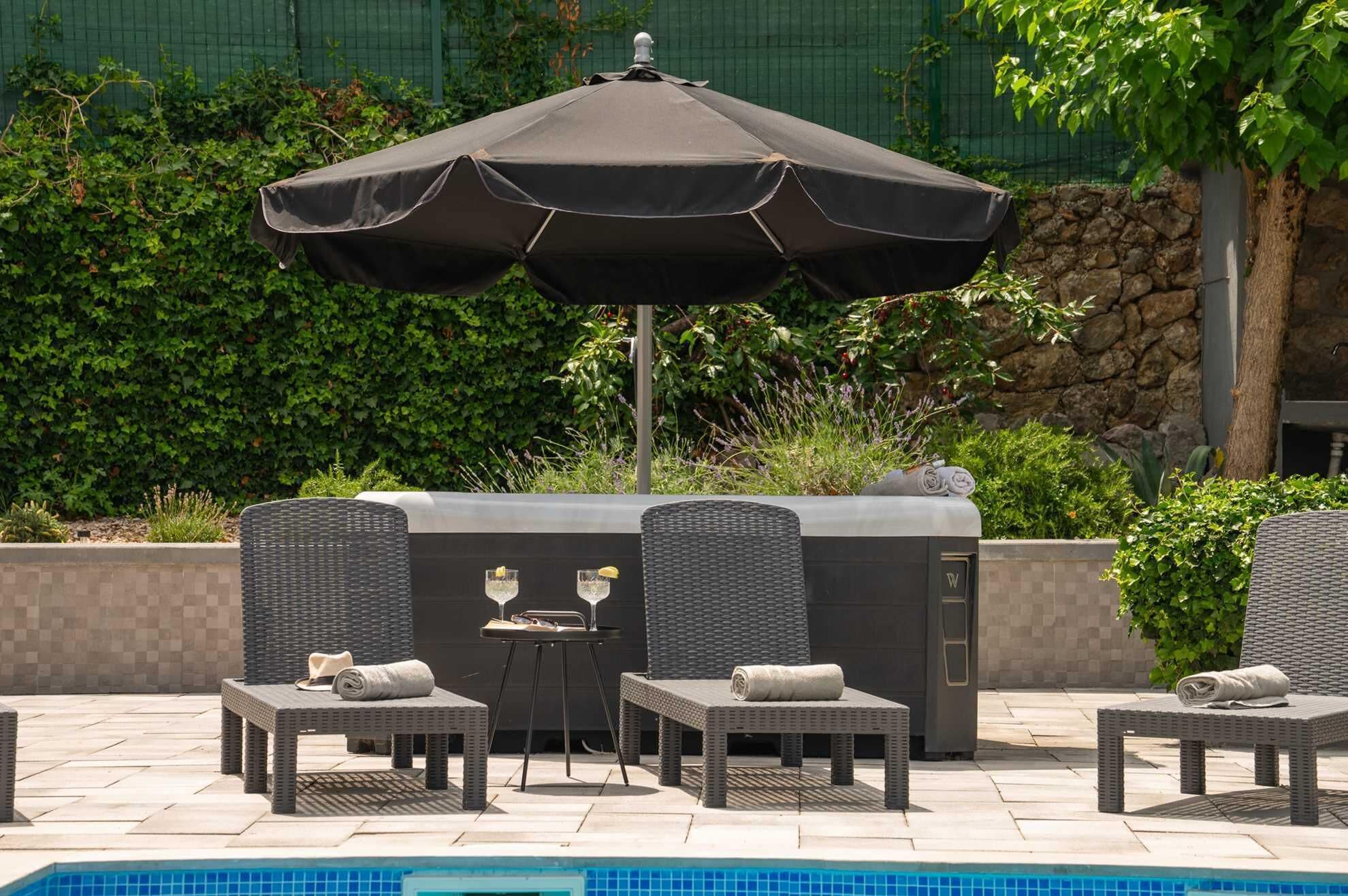 A poolside area with a barbecue grill, lounge chairs, and an umbrella.