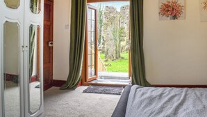 A room with a bed, a door, and a view of the outdoors. - 4 bedroom accommodation in Carmarthen (Carmarthen)