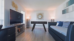 A modern living room with a flat-screen TV, a sofa, a coffee table, and a wall-mounted decorative piece.