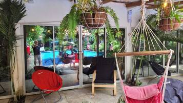 A modern indoor space with a pool, hammocks, and various seating areas.