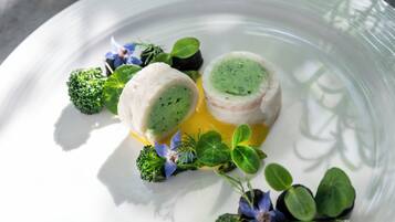 Un plato blanco con un alimento verde y blanco, brócoli y pequeñas flores azules.