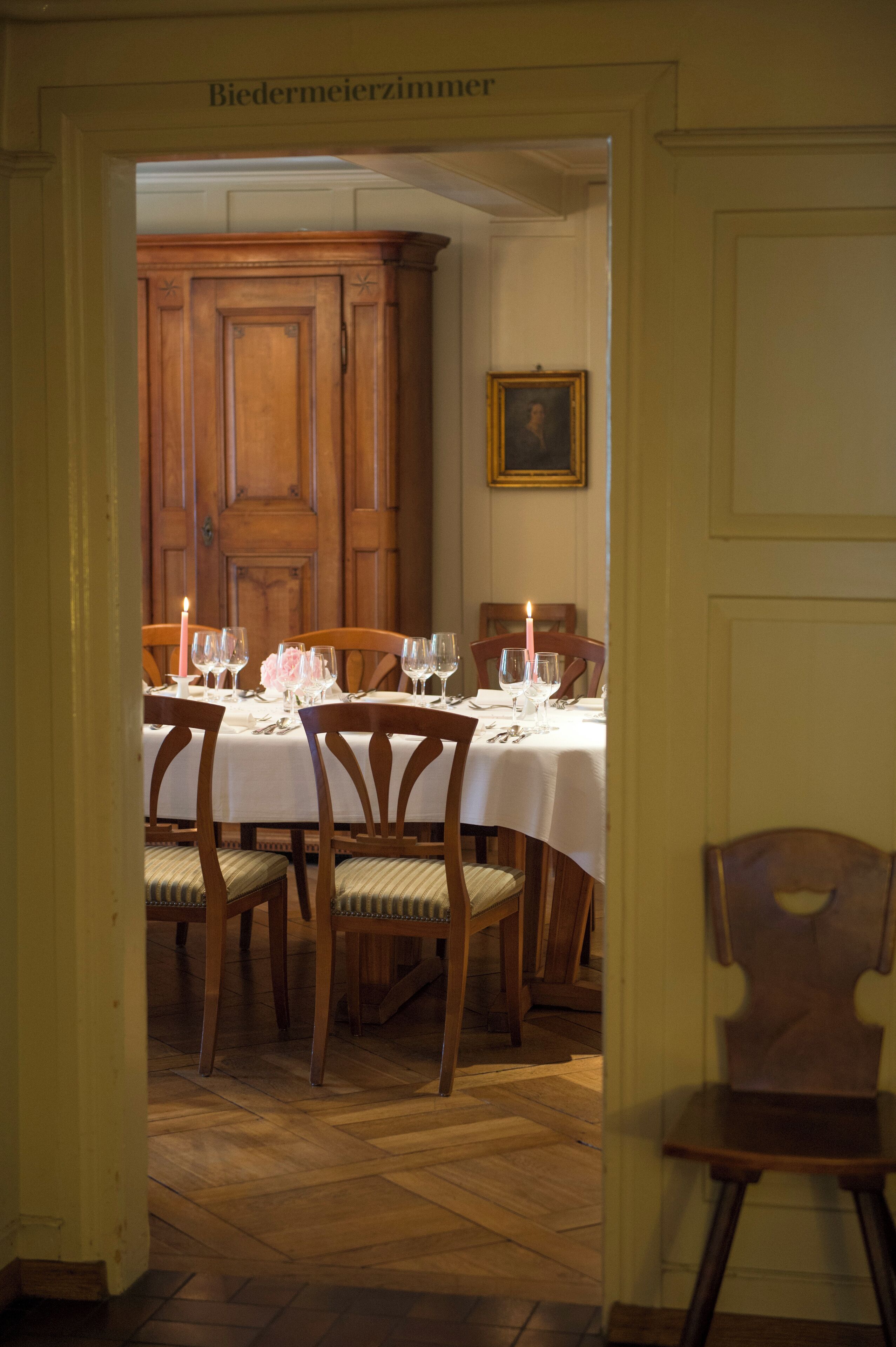 Ein Esszimmer mit Holzschrank, einem für vier Personen gedeckten Tisch und einem gerahmten Bild an der Wand.
