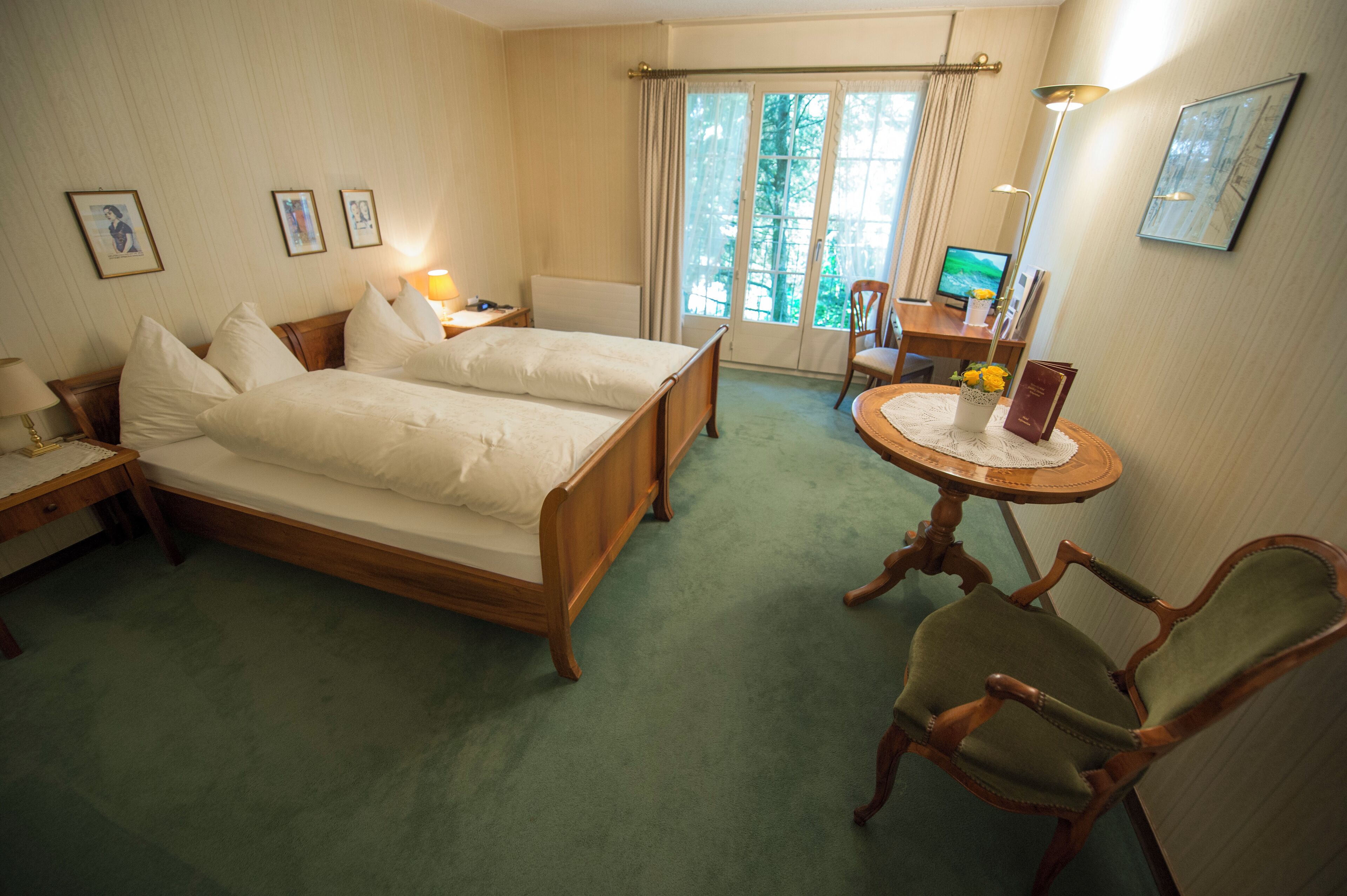 A hotel room with two beds, a desk, a chair, and a window with curtains.