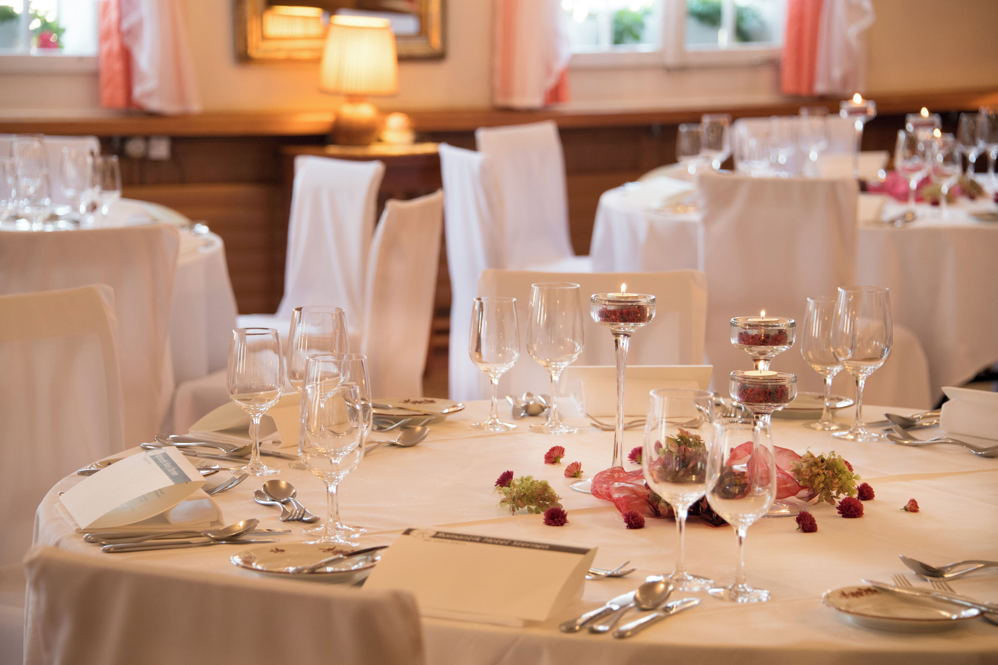A well-set dining table with multiple wine glasses, water glasses, and cutlery, arranged neatly on a white tablecloth.