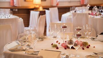A well-set dining table with multiple wine glasses, water glasses, and cutlery, arranged neatly on a white tablecloth.