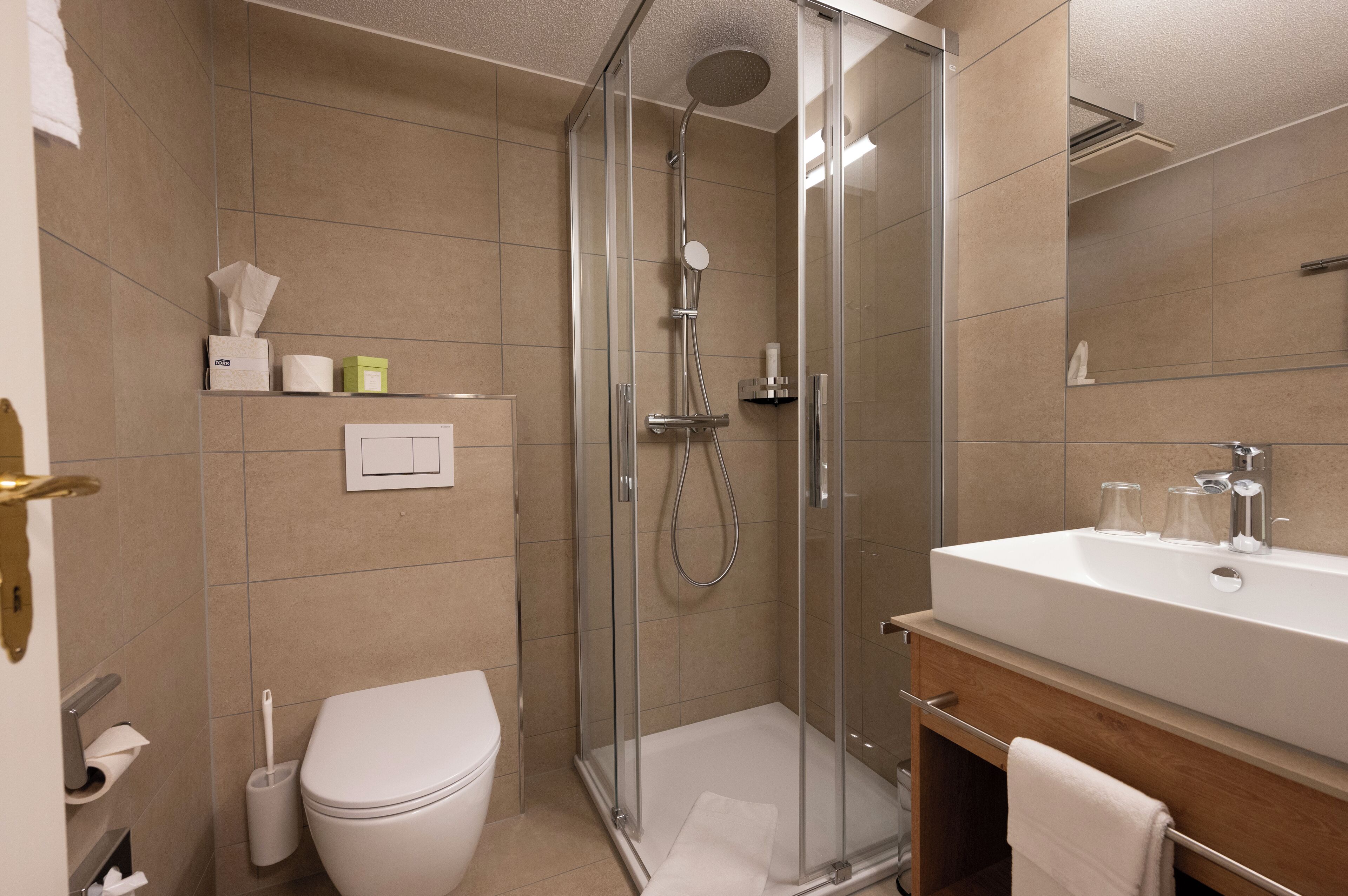 A modern bathroom with a glass-enclosed shower, a white sink, and a toilet.