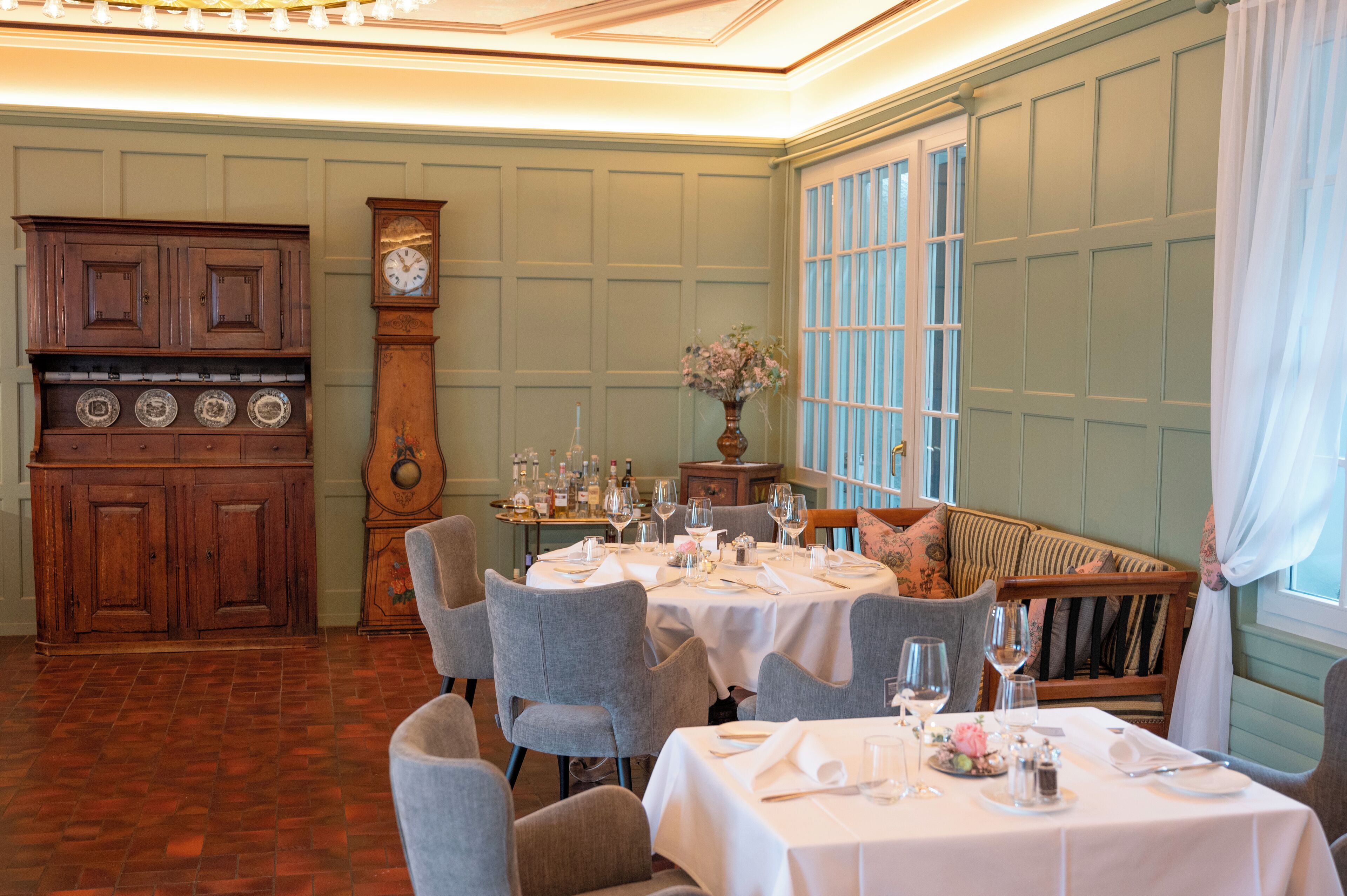 A dining area with wooden furniture, a clock, and a vase with flowers.