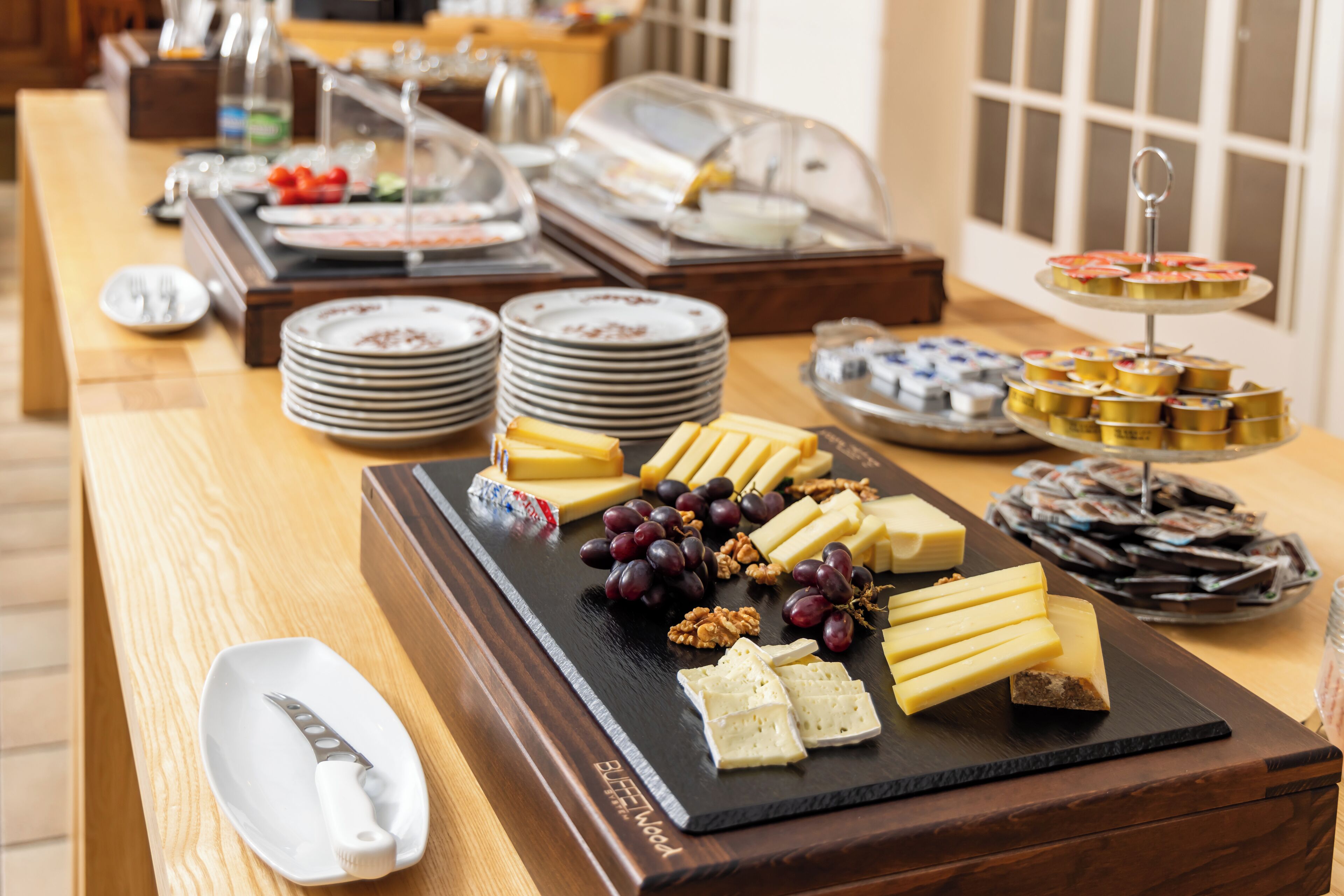 A buffet with various cheeses, fruits, and desserts.