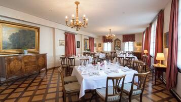 Un comedor formal con varias mesas dispuestas para el servicio, sillas de madera y un cuadro grande en la pared.