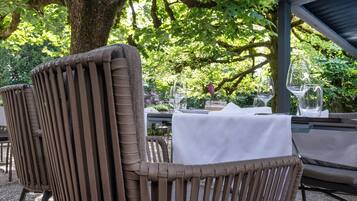 An outdoor seating area with wicker chairs and a table covered with a white tablecloth.