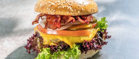 A burger with lettuce, tomato, cheese, bacon, and a sesame seed bun.