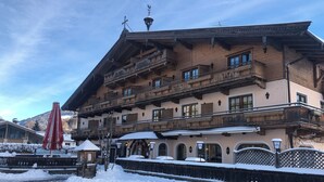 Un hotel de diverses plantes amb balcons, terra coberta de neu i cel serena.