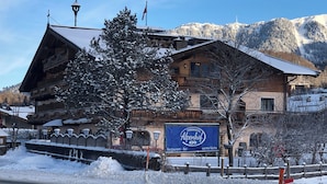 Edifici de fusta tradicional amb un cartell de 'Ferienhotel Alpenhof' que indica un restaurant i un bar.