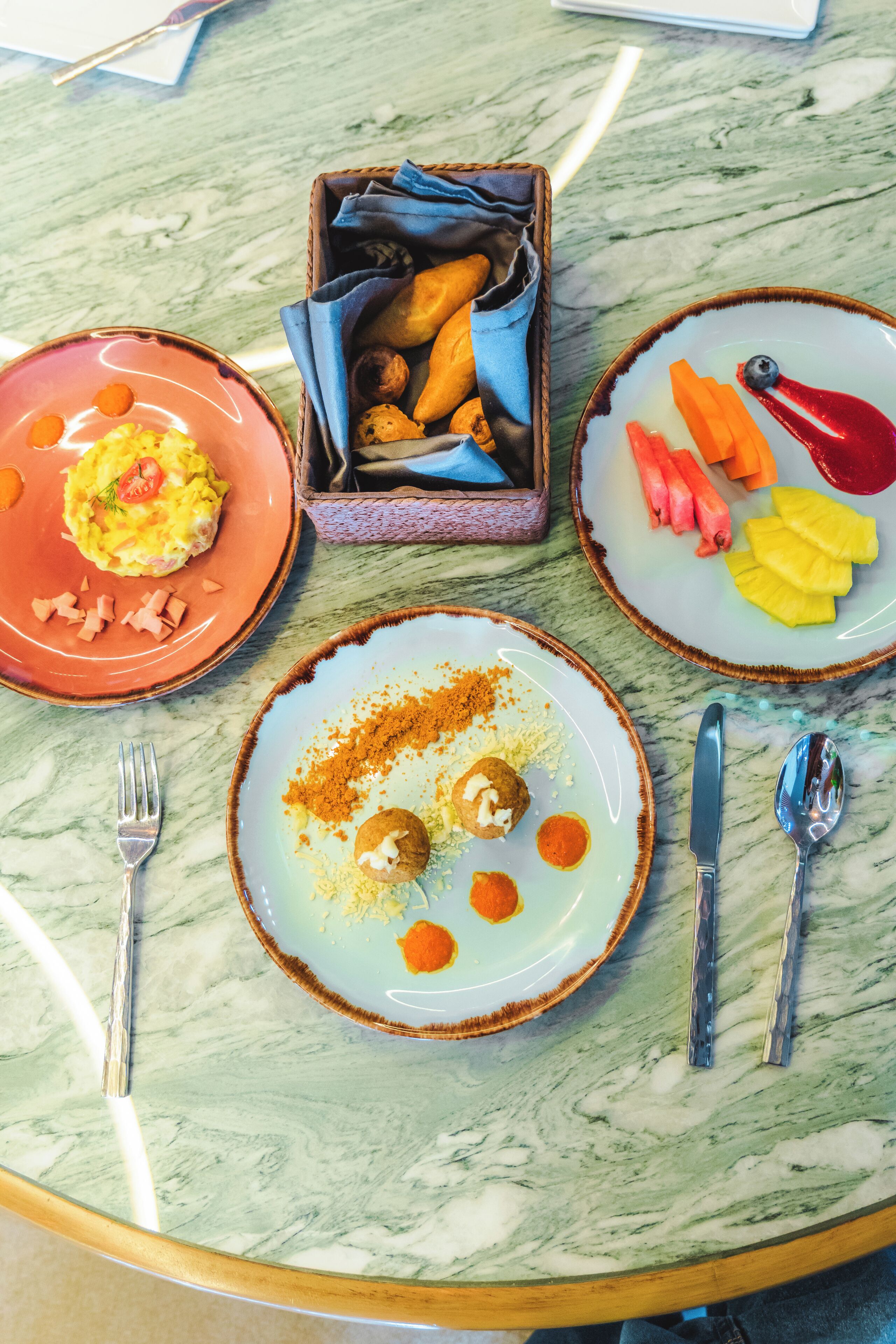 Una mesa con tres platos de comida, un reposa servilletas y cubiertos.
