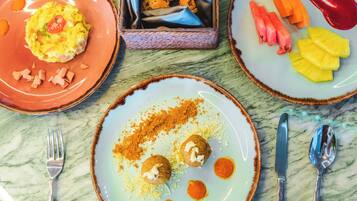 A table with three plates of food, a napkin holder, and cutlery.