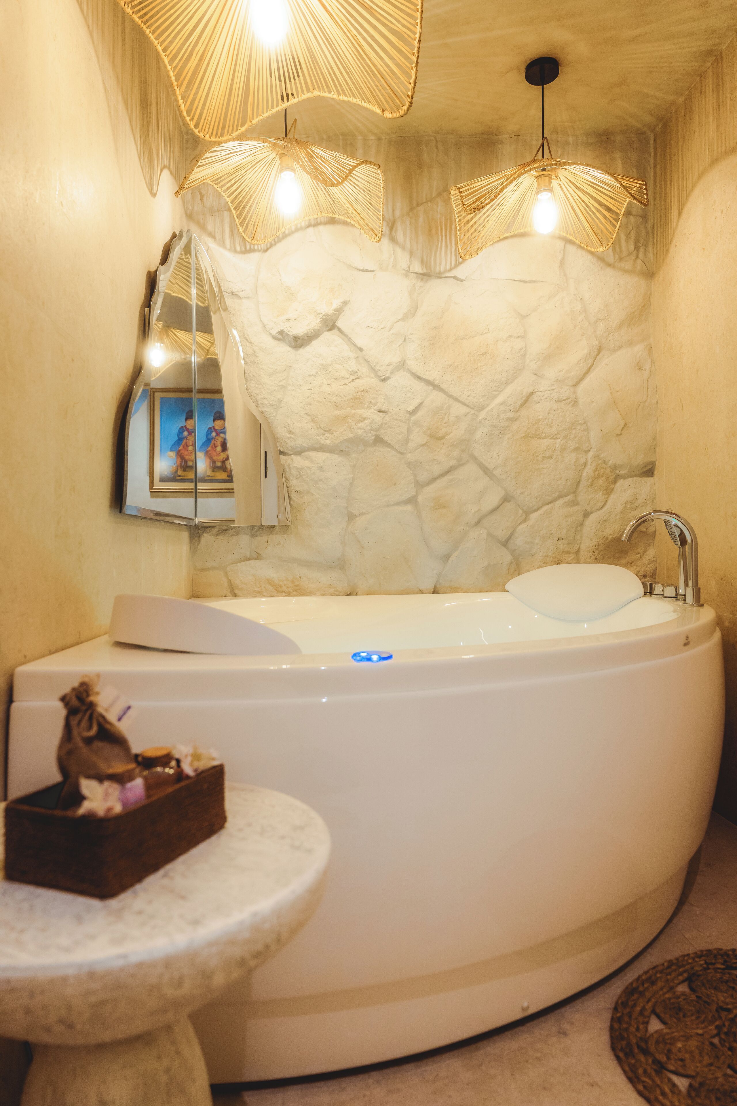 Un baño con una bañera grande, un lavabo redondo y una pequeña mesa con un adorno.