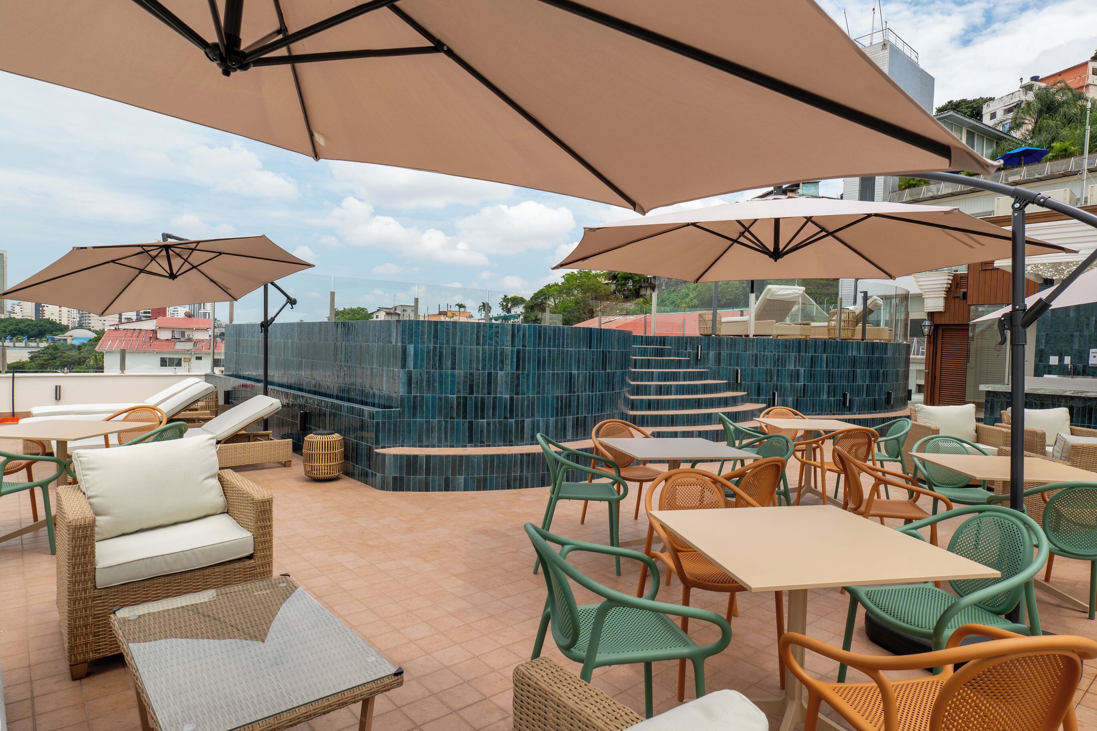 An outdoor patio area with wicker furniture, large umbrellas, and a blue-tiled wall.