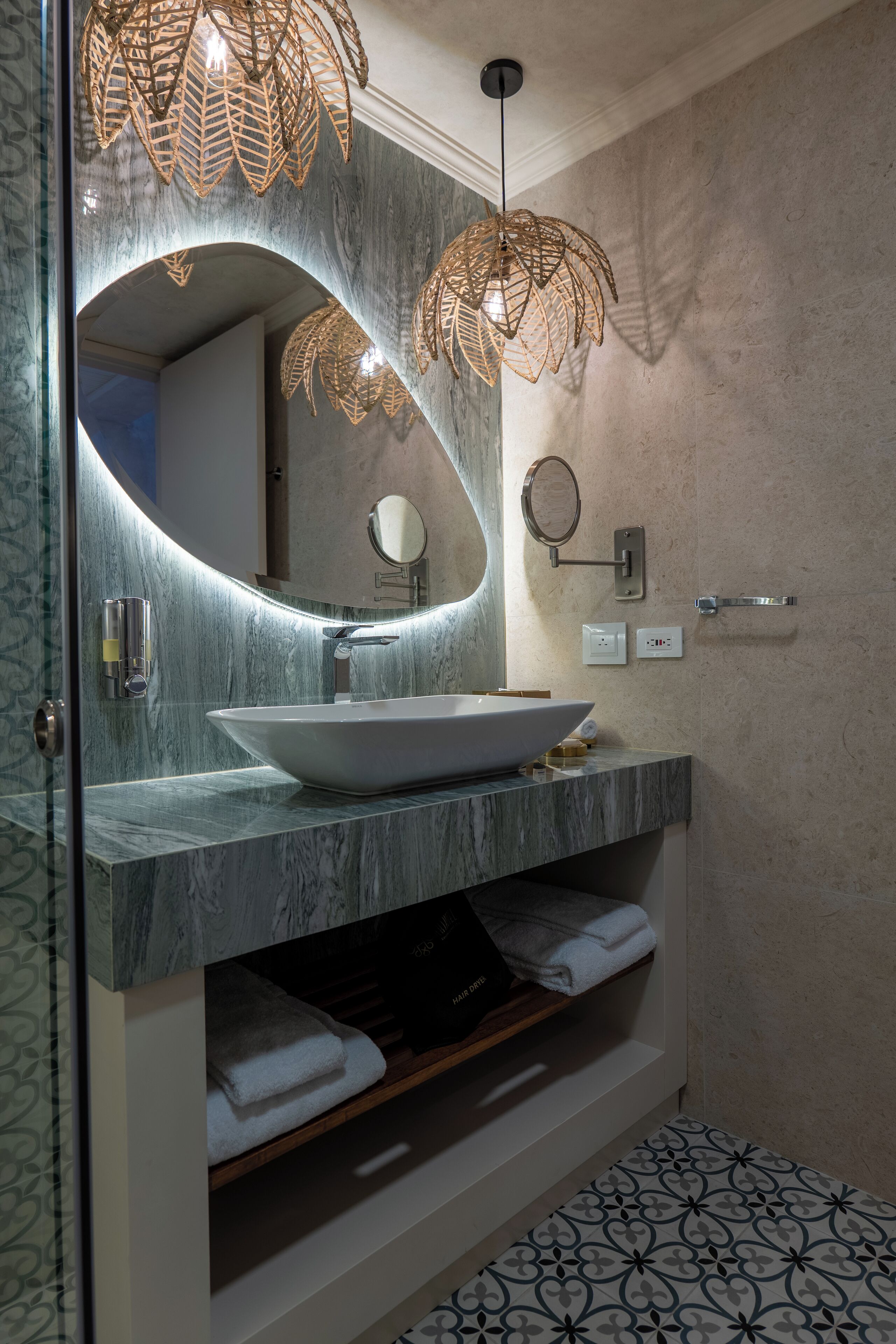 Un baño moderno con un lavamanos ovalado grande, un espejo y una lámpara colgante.